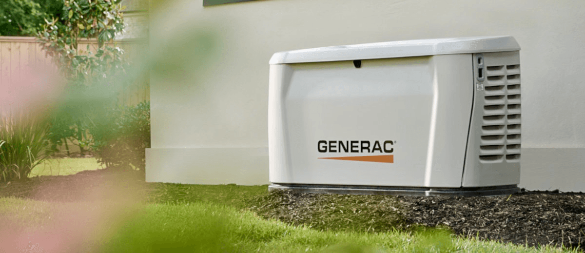White Generac home standby generator installed on a mulch bed next to a residential house.